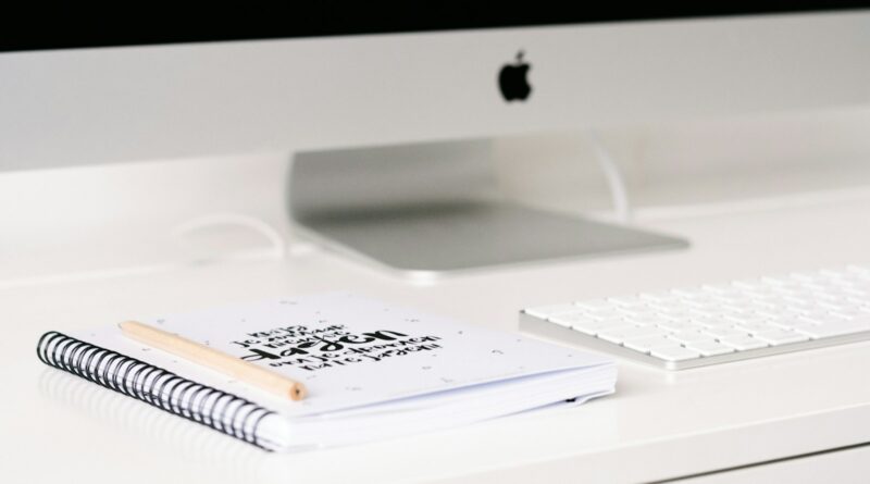 white book beside iMac and keyboard on table